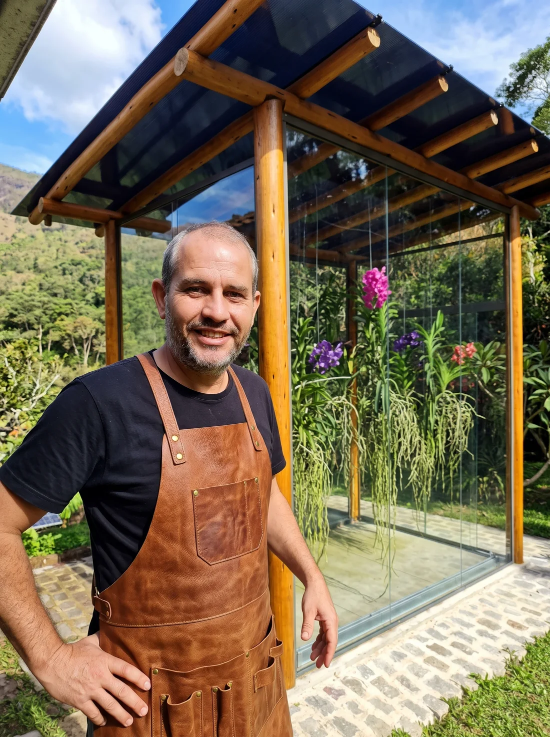 Marcus, proprietário da Vidraçaria Petrópolis, ao lado de um orquidário em vidro